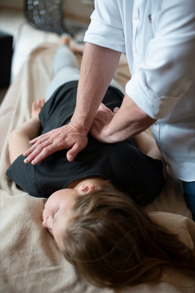 A physical therapist pressing along a patient's upper back during manual therapy