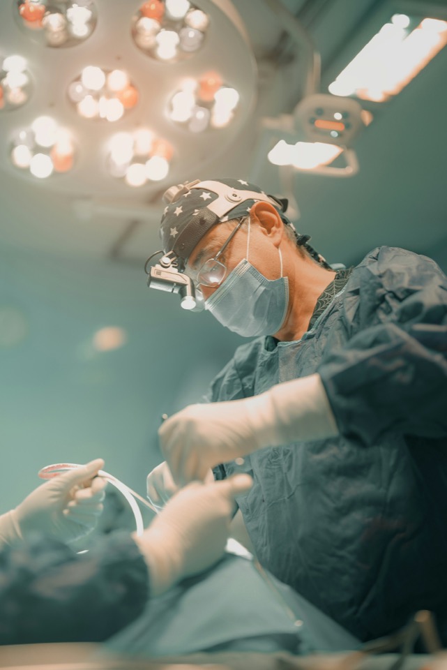 A surgeon wearing a headlight and magnifying loupes